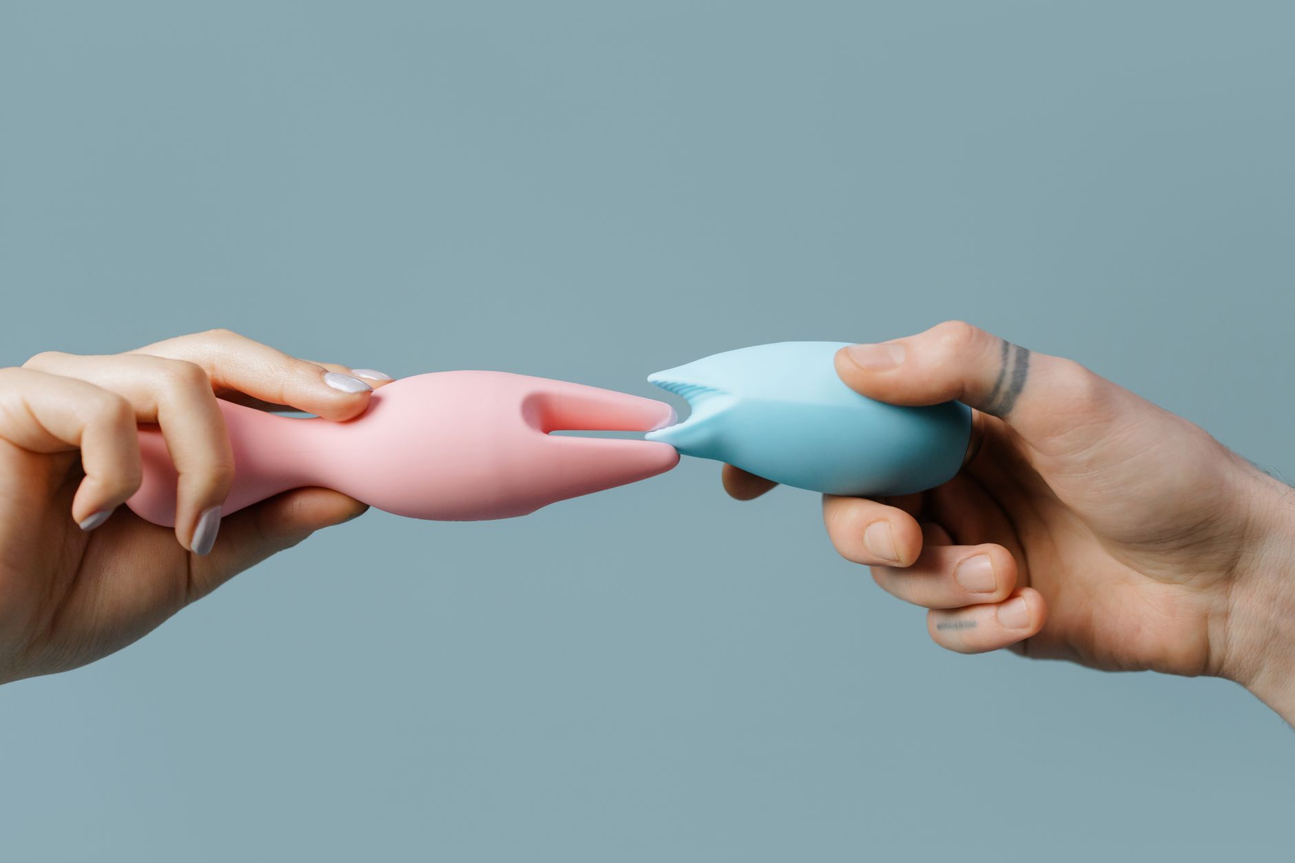 Hands holding colorful silicone vibrators and pleasure toys