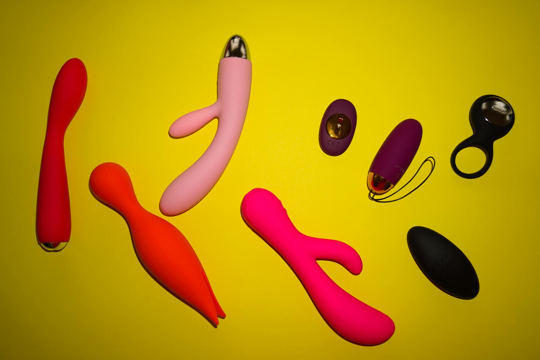 Close-up of a hand holding a sleek vibrator against a minimalistic backdrop