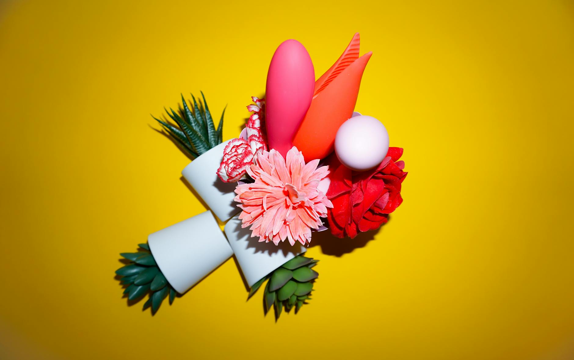 A hand reaching over a collection of colorful clitoral vibrators on a table.